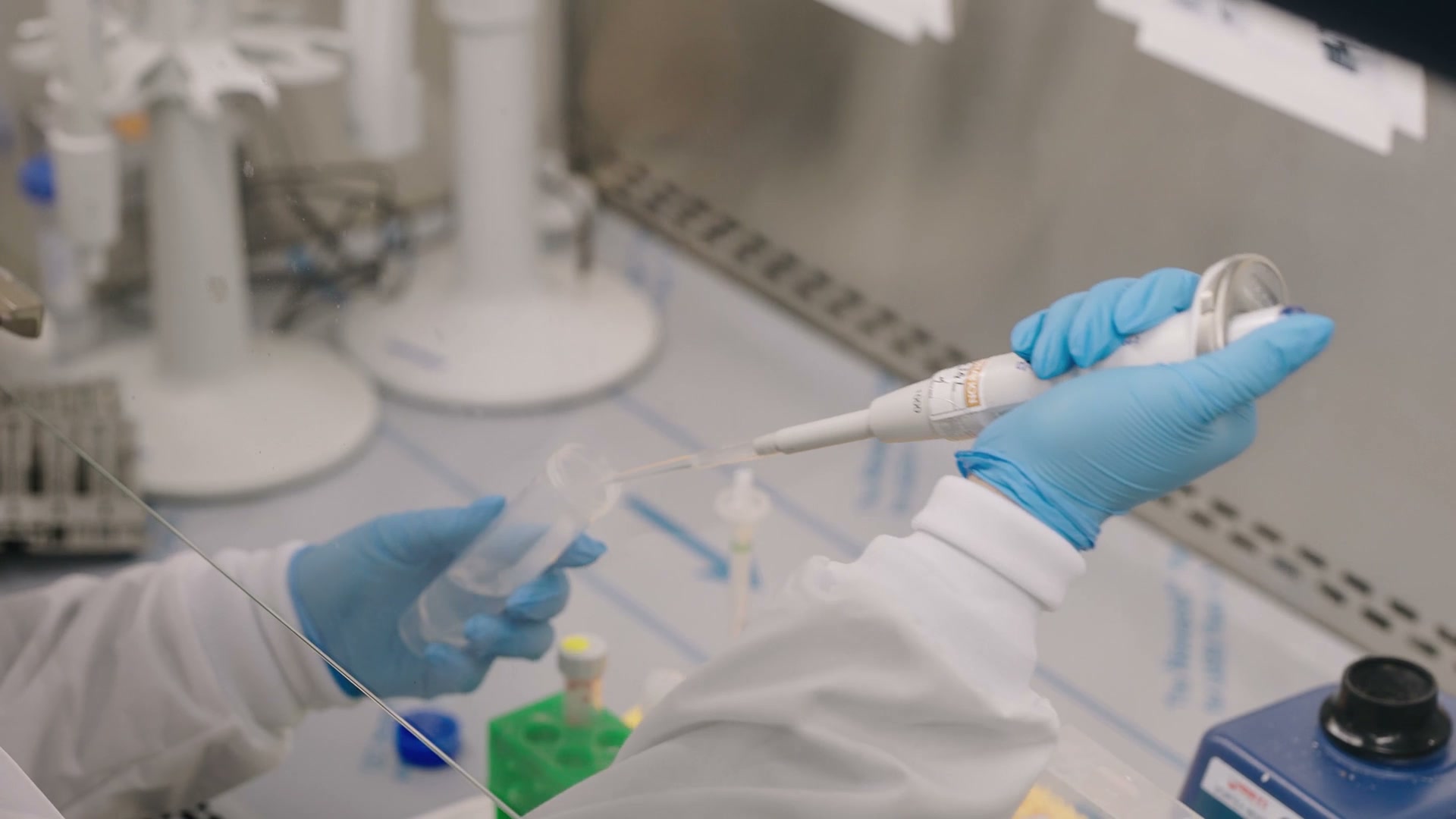 Technologist pipetting a specimen under the hood during testing